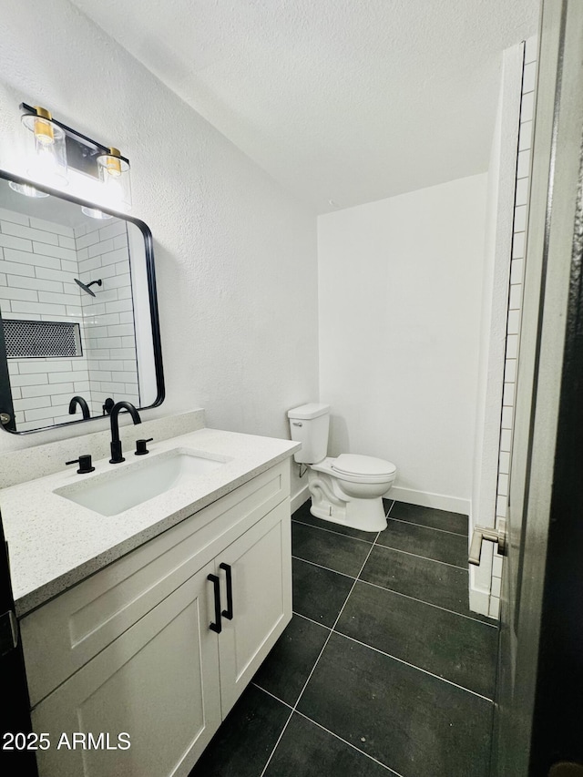bathroom featuring tile patterned floors, toilet, tiled shower, vanity, and a textured ceiling