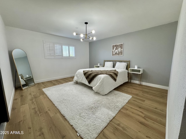 bedroom featuring a chandelier, wood finished floors, and baseboards