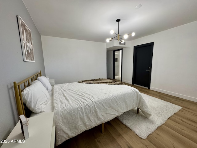 bedroom featuring wood finished floors, a chandelier, and baseboards
