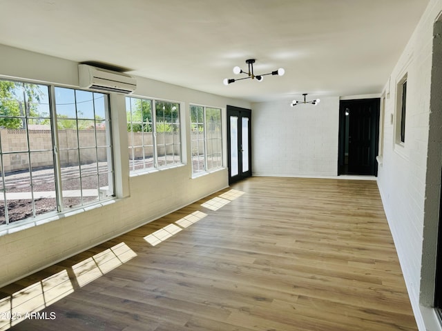 unfurnished sunroom featuring a wall mounted air conditioner and a chandelier