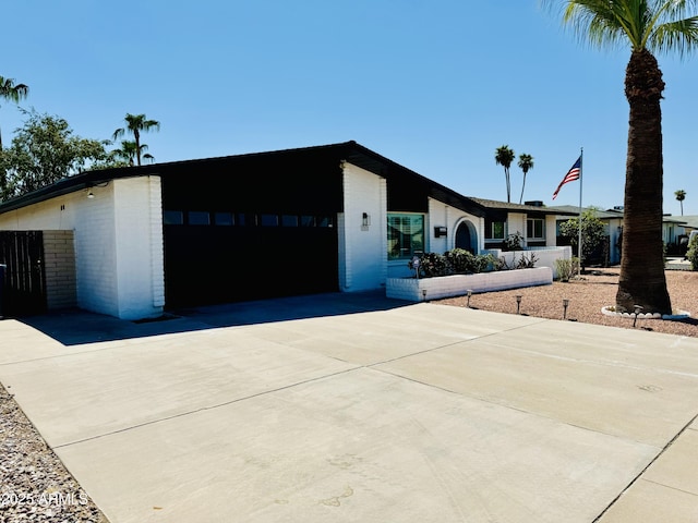 mid-century home with brick siding, driveway, and a garage