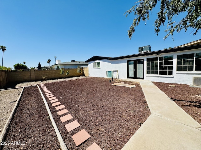 fenced backyard with central AC unit and french doors