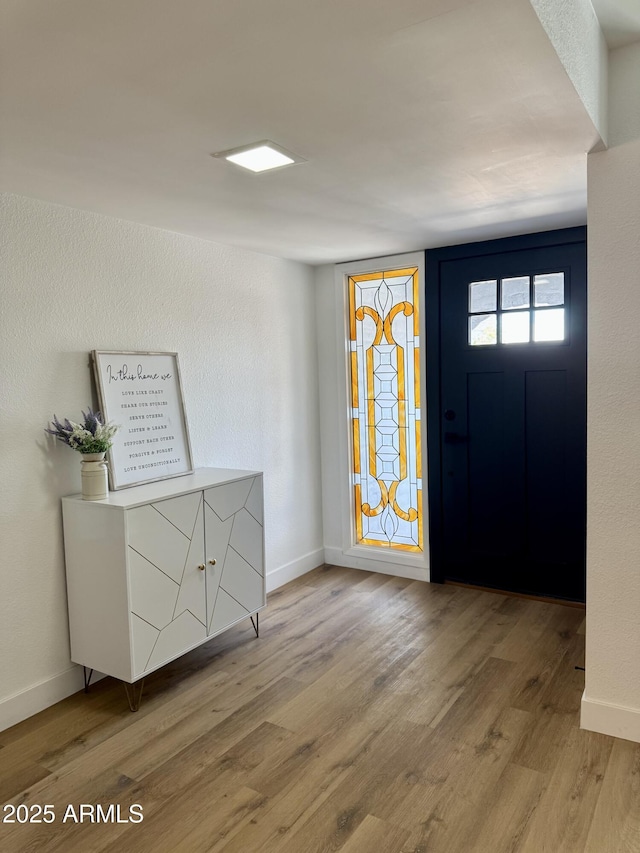 foyer entrance with wood finished floors and baseboards