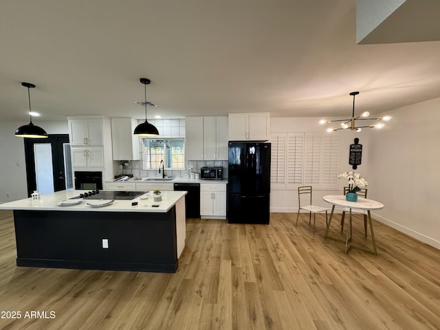 kitchen with black appliances, a sink, light countertops, backsplash, and white cabinets