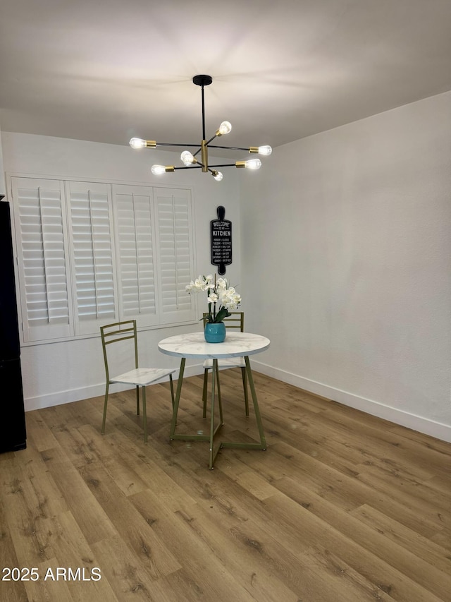 unfurnished dining area featuring a chandelier, wood finished floors, and baseboards