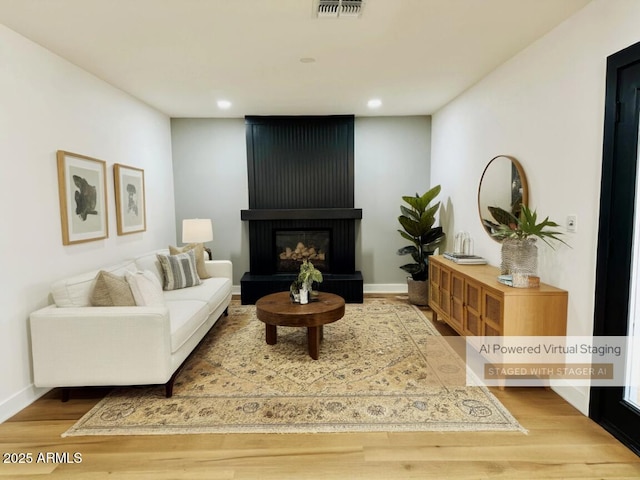 living area with wood finished floors, recessed lighting, a large fireplace, and baseboards