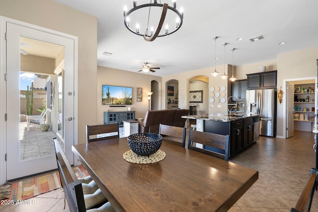 dining space featuring arched walkways, visible vents, light tile patterned floors, and an inviting chandelier
