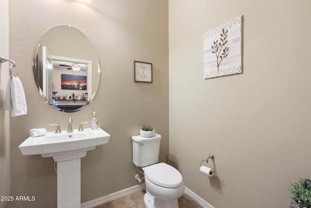 half bath with tile patterned floors, baseboards, a ceiling fan, and toilet