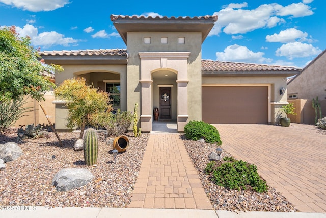 mediterranean / spanish house with a tiled roof, stucco siding, and a garage
