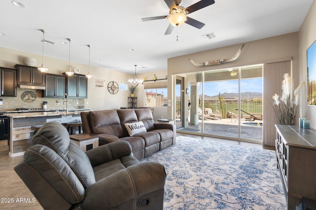 living room with ceiling fan with notable chandelier and visible vents