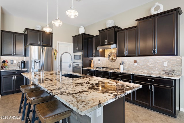 kitchen with decorative backsplash, a breakfast bar, light stone counters, a sink, and stainless steel appliances