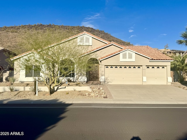 view of front of property with a garage, concrete driveway, a tile roof, and stucco siding