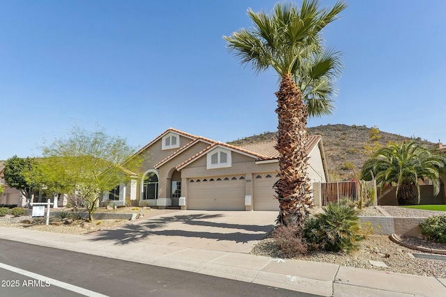 view of front facade with concrete driveway, a tile roof, an attached garage, fence, and stucco siding