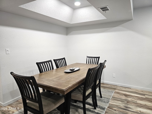 dining area with hardwood / wood-style floors and a tray ceiling