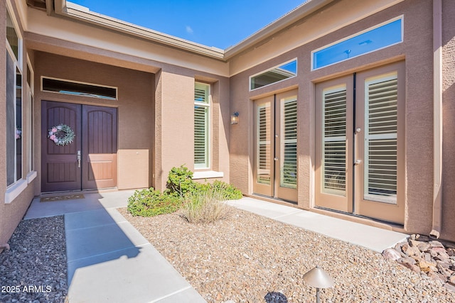 view of exterior entry with stucco siding and french doors