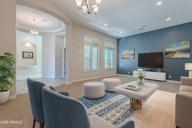 carpeted living area with arched walkways, recessed lighting, baseboards, and an inviting chandelier