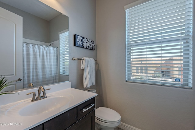 bathroom with vanity, a shower with shower curtain, toilet, and baseboards