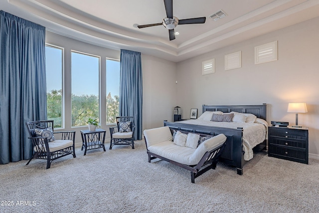 carpeted bedroom featuring visible vents, a raised ceiling, baseboards, and ceiling fan