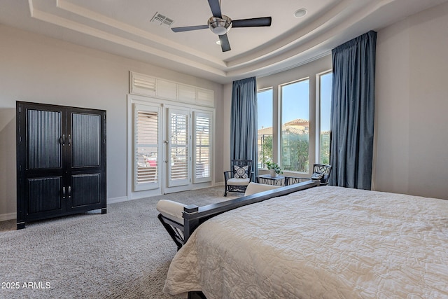 bedroom featuring visible vents, access to outside, a tray ceiling, carpet, and baseboards