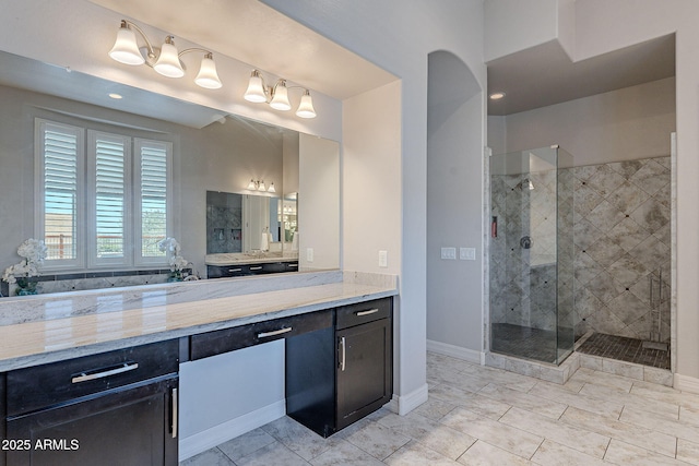 bathroom featuring vanity, baseboards, and a stall shower