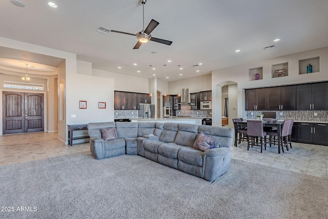 living room featuring light tile patterned floors, arched walkways, and visible vents