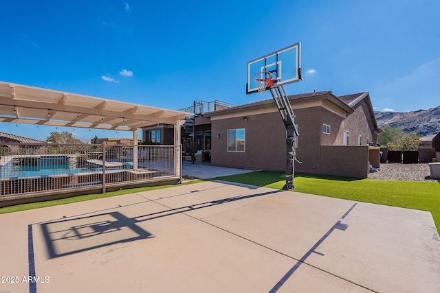 view of basketball court featuring a yard, fence, a mountain view, and a pergola