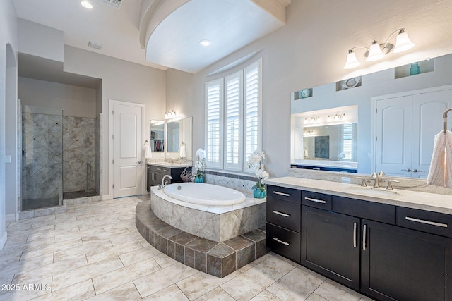 full bath with visible vents, two vanities, a sink, a shower stall, and a bath