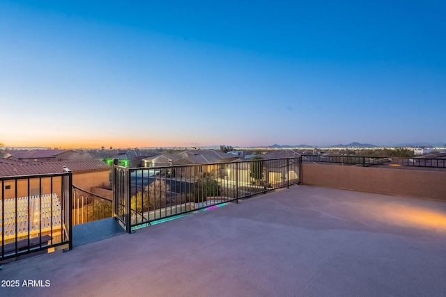 patio terrace at dusk featuring a mountain view, a residential view, and a balcony