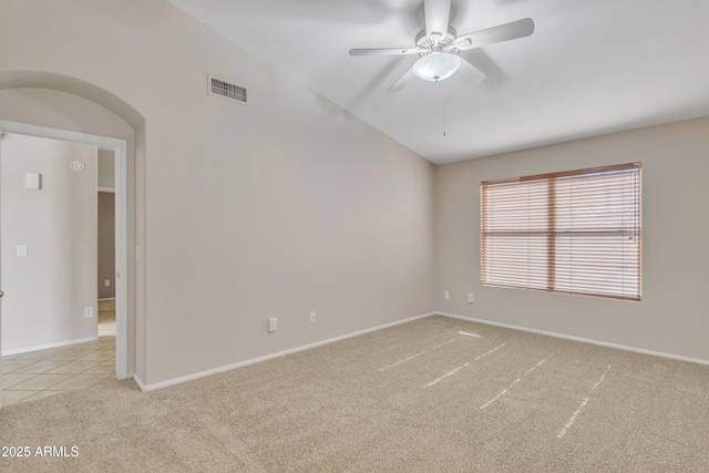 spare room with ceiling fan, vaulted ceiling, and light carpet