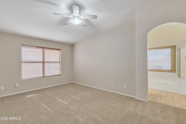 empty room with ceiling fan, light colored carpet, a healthy amount of sunlight, and vaulted ceiling