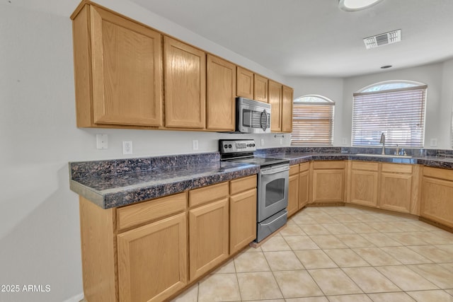 kitchen featuring appliances with stainless steel finishes, sink, light tile patterned floors, and light brown cabinetry