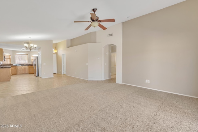 unfurnished living room featuring light carpet, sink, ceiling fan with notable chandelier, and lofted ceiling