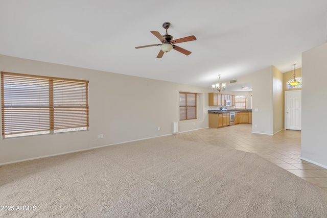 unfurnished living room with vaulted ceiling, ceiling fan with notable chandelier, and light colored carpet