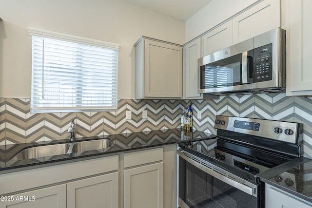 kitchen featuring white cabinets, appliances with stainless steel finishes, dark stone counters, and sink