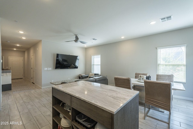 kitchen with ceiling fan, a center island, and dark brown cabinets