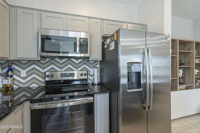 kitchen featuring tasteful backsplash, gray cabinets, dark stone counters, and stainless steel appliances