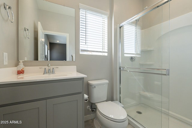 bathroom with plenty of natural light, vanity, a shower with door, and toilet