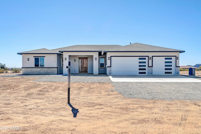 prairie-style home featuring a garage, driveway, and stucco siding