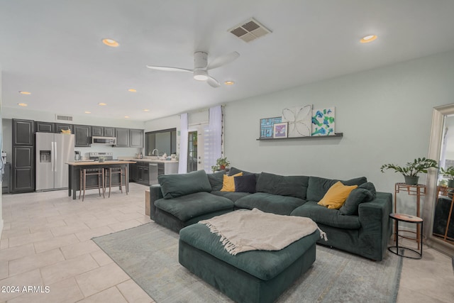 living room with ceiling fan, sink, and light tile patterned floors