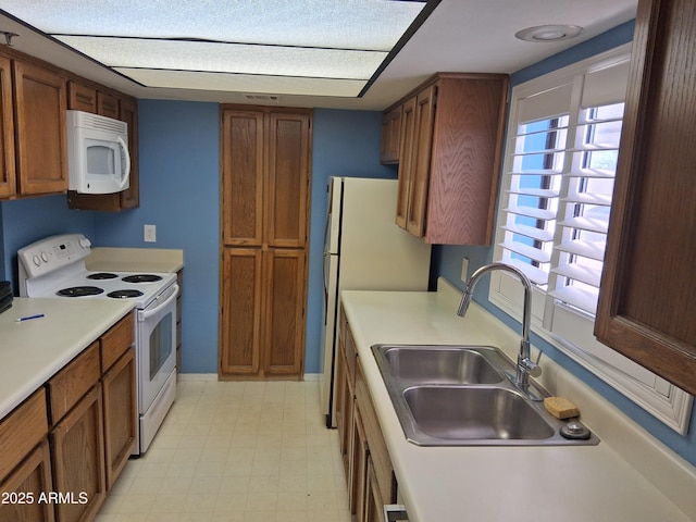 kitchen featuring a sink, brown cabinetry, and white appliances