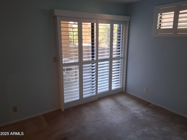carpeted empty room featuring baseboards