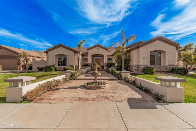 mediterranean / spanish home with stone siding, a tile roof, a front lawn, and stucco siding