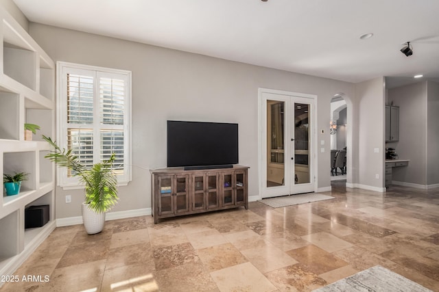 living room featuring arched walkways, french doors, and baseboards