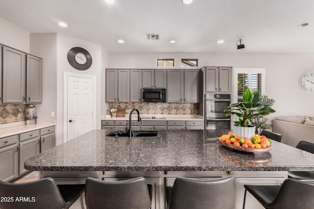 kitchen with stainless steel appliances, a kitchen island with sink, visible vents, and a kitchen breakfast bar