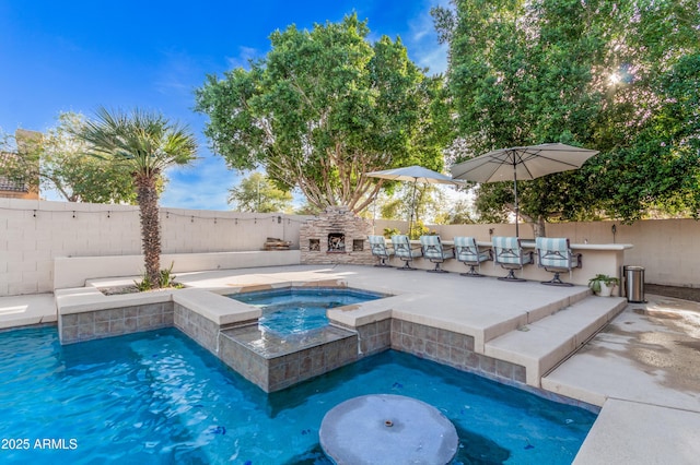 view of swimming pool featuring exterior fireplace, a fenced backyard, an in ground hot tub, an outdoor bar, and a fenced in pool