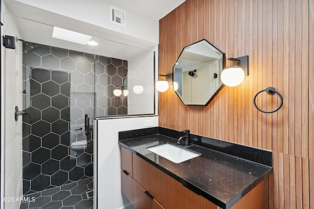 bathroom with tile patterned floors, tiled shower, toilet, and vanity