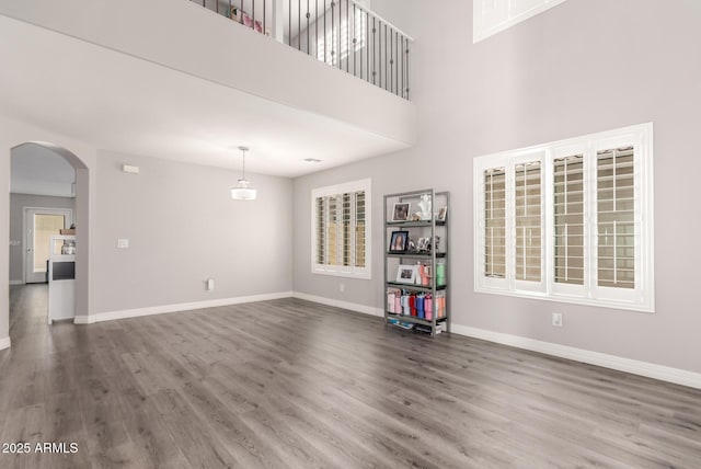 4142 E Sandy Way, Gilbert, AZ 85297 - unfurnished living room featuring wood finished floors, arched walkways, and baseboards