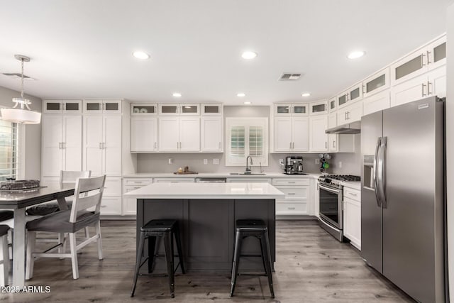 4142 E Sandy Way, Gilbert, AZ 85297 - kitchen with appliances with stainless steel finishes, a sink, under cabinet range hood, a breakfast bar area, and a kitchen island