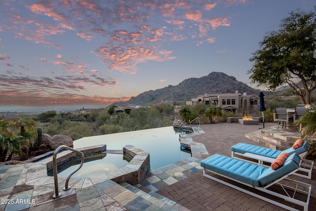 patio terrace at dusk with an in ground hot tub and a mountain view