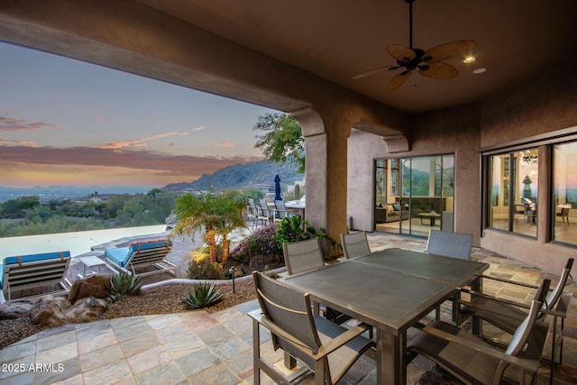 patio terrace at dusk with a mountain view and ceiling fan